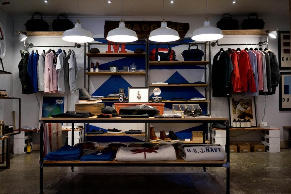 Shop interior with displays of folded clothes under pendant lamps