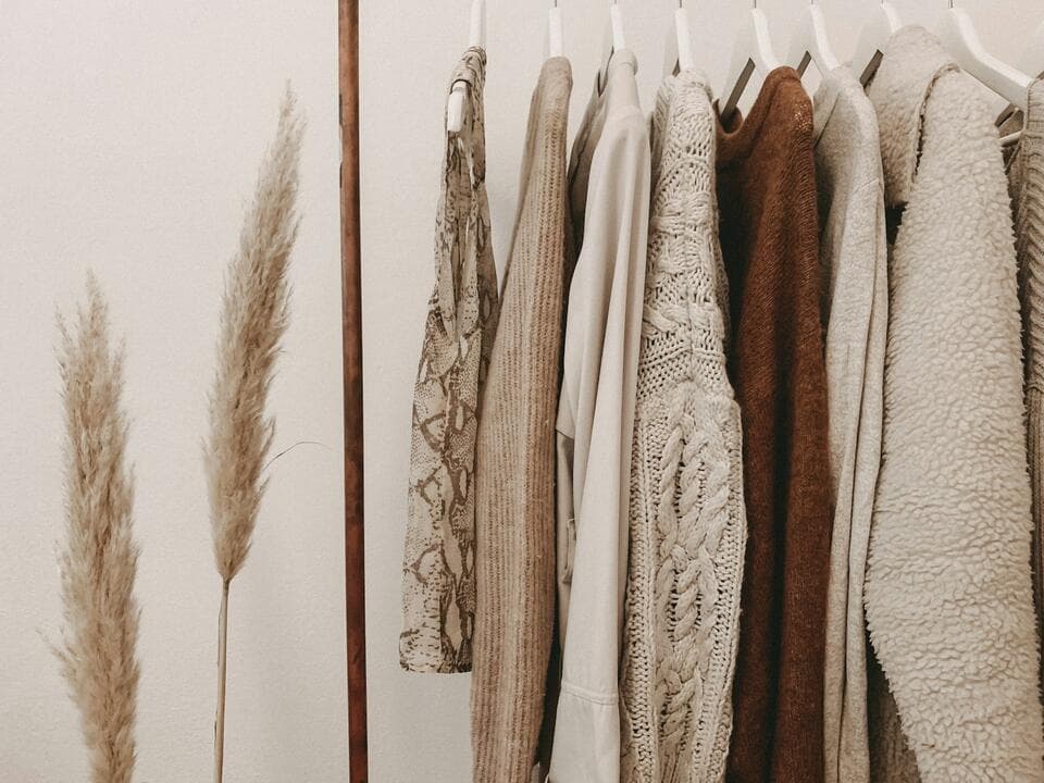 Knitwear in cream and brown hanging on wooden hangers