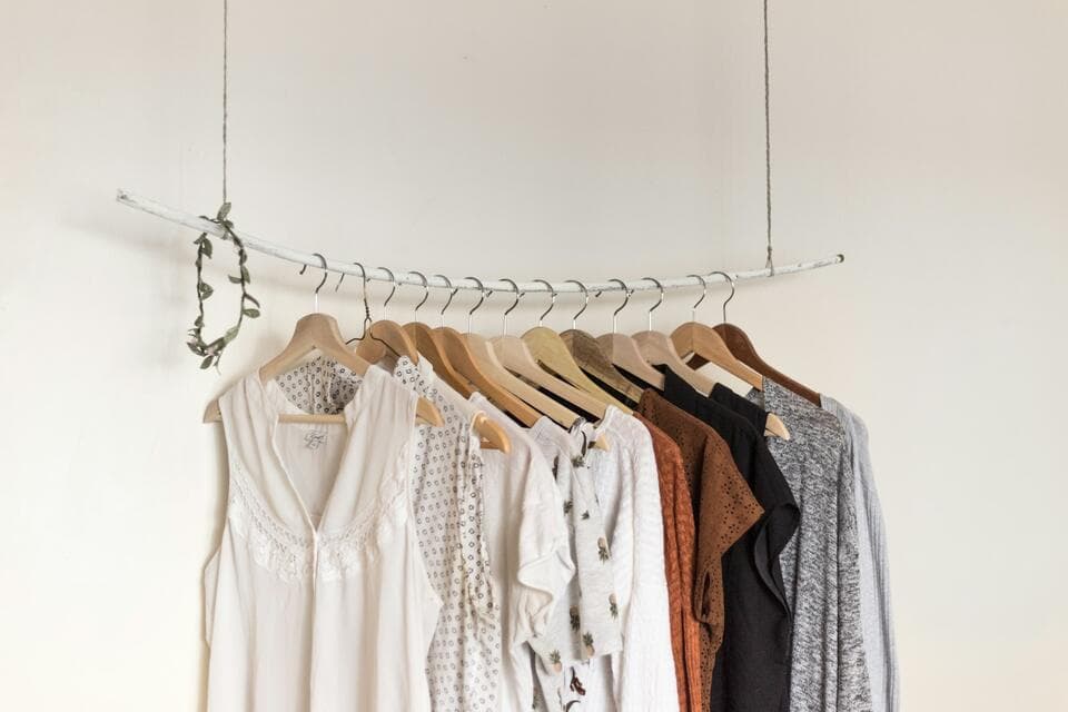 Blouses and tops hanging on a rail against a white wall