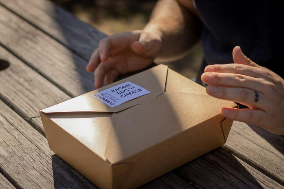 Hands holding a kraft box with a shipping label on a wooden table