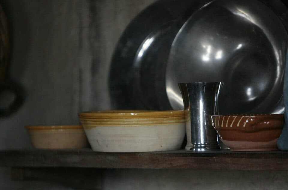 Stoneware pots and bowls on a dark wooden shelf