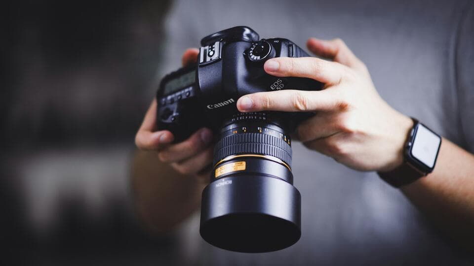 Hands holding a DSLR camera with a large lens